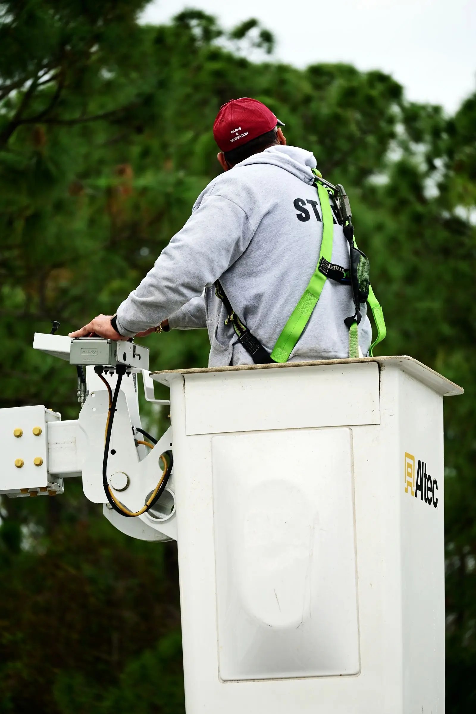 Worker in a safety harness operating the controls of a bucket lift