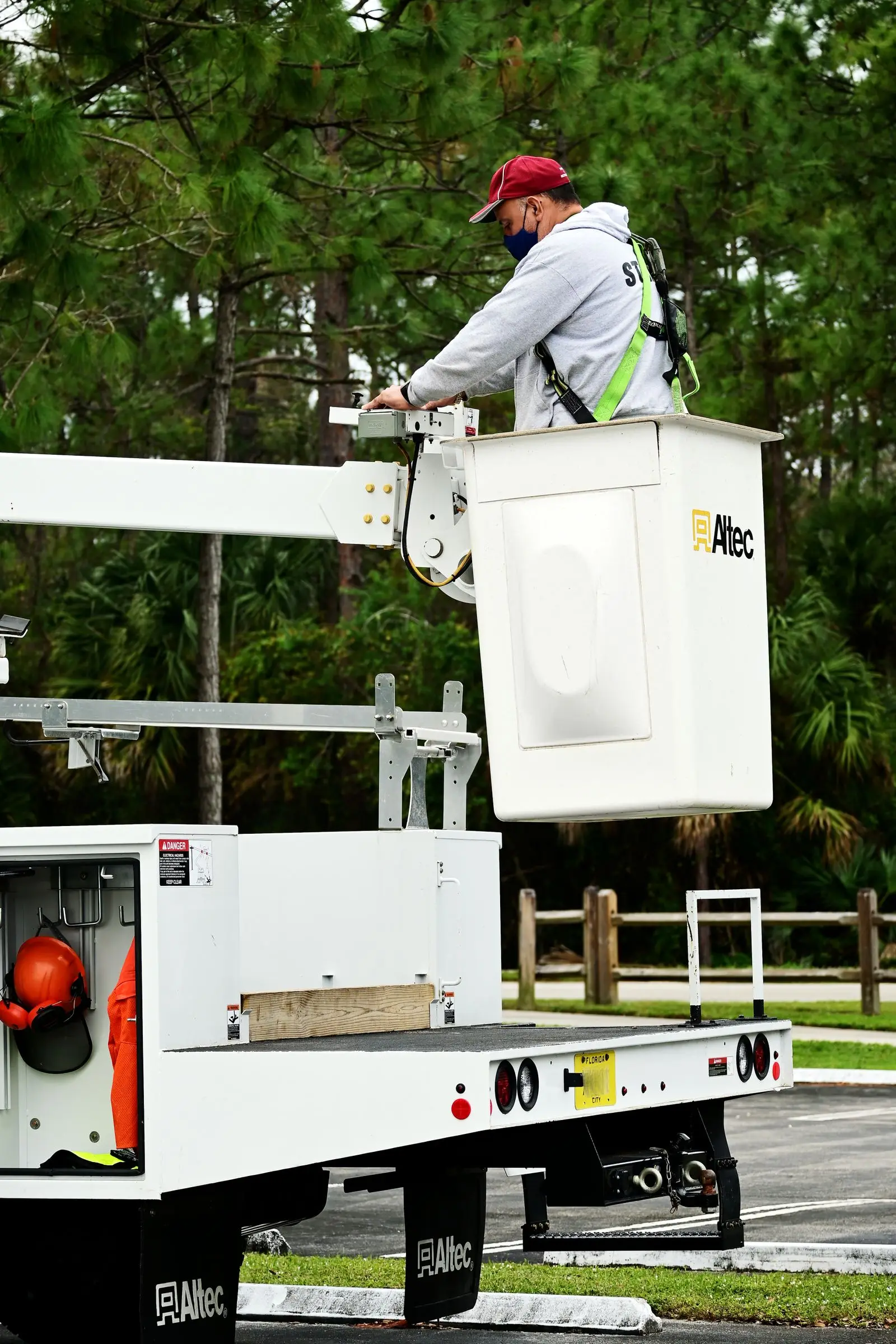 Worker in a harness standing in the bucket of an aerial lift truck